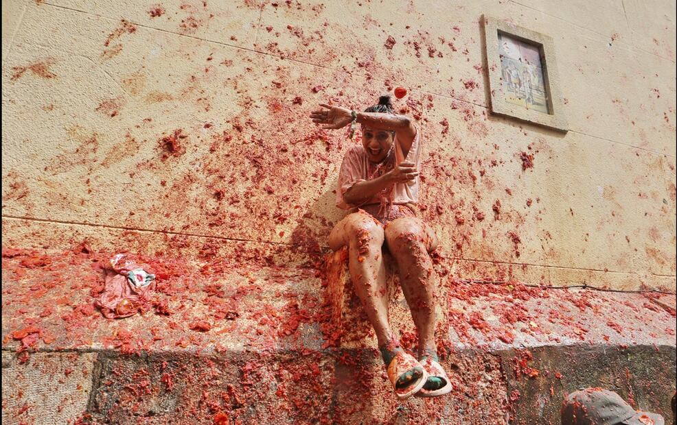 Una mujer se cubre mientras participantes le lanzan tomates durante la Tomatina, en el pueblo valenciano de Buñol, España, el miércoles 27 de agosto de 2025. Foto: AP