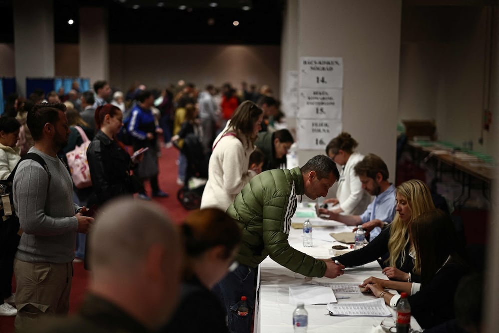 Votantes húngaros recogen sus boletas, en una casilla electoral instalada en Londres. FOTO: HENRYNICHOLLS. AFP