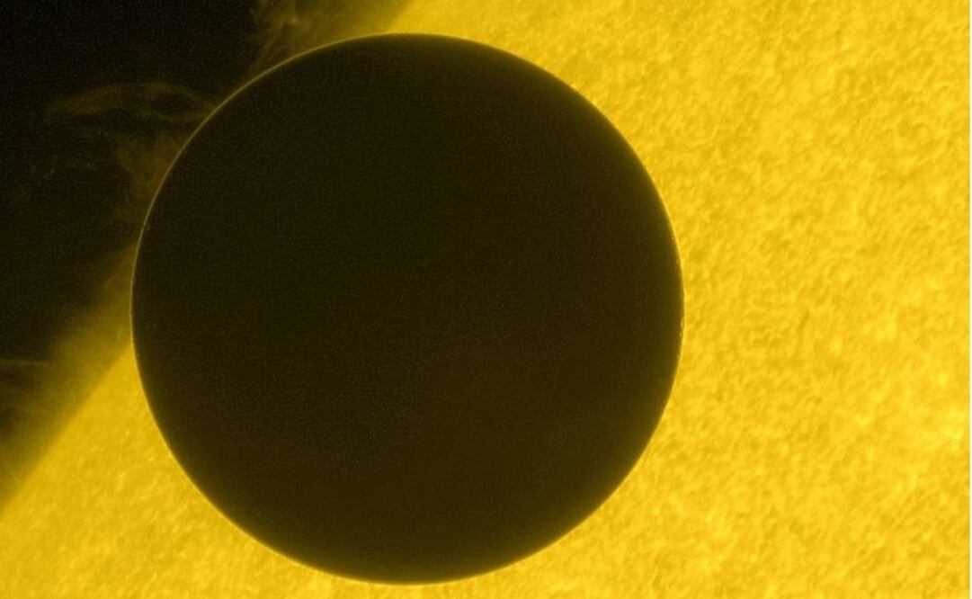 Esta imagen de Venus muestra el comienzo del viaje a través de la cara del sol. Su atmósfera es visible como una delgada frontera que brilla intensamente en la parte superior izquierda del planeta.