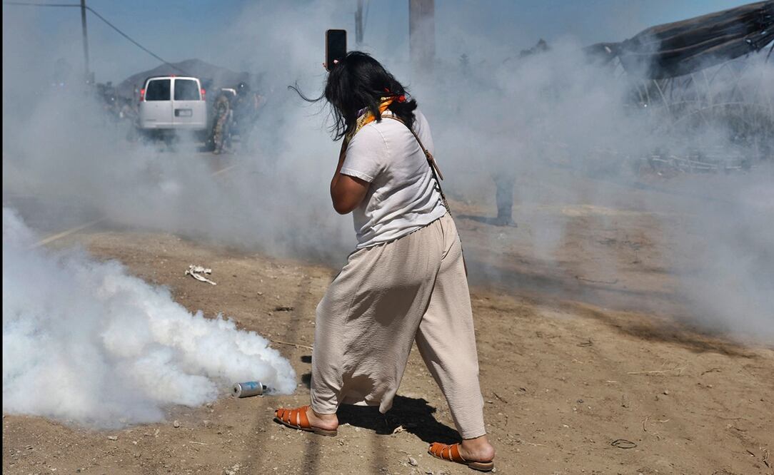 Una mujer graba los enfrentamientos durante una redada de inmigración del ICE en una granja de cannabis con licencia cerca de Camarillo, California, el 10 de julio de 2025. Manifestantes se enfrentaron a los agentes federales durante horas frente a la granja, en la comunidad de trabajadores agrícolas del condado de Ventura. Foto: AFP