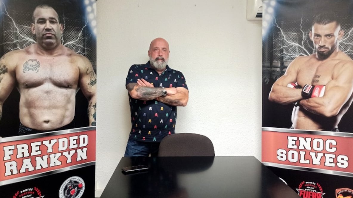 Jorge Fe posa entre la foto de dos de sus empleados.