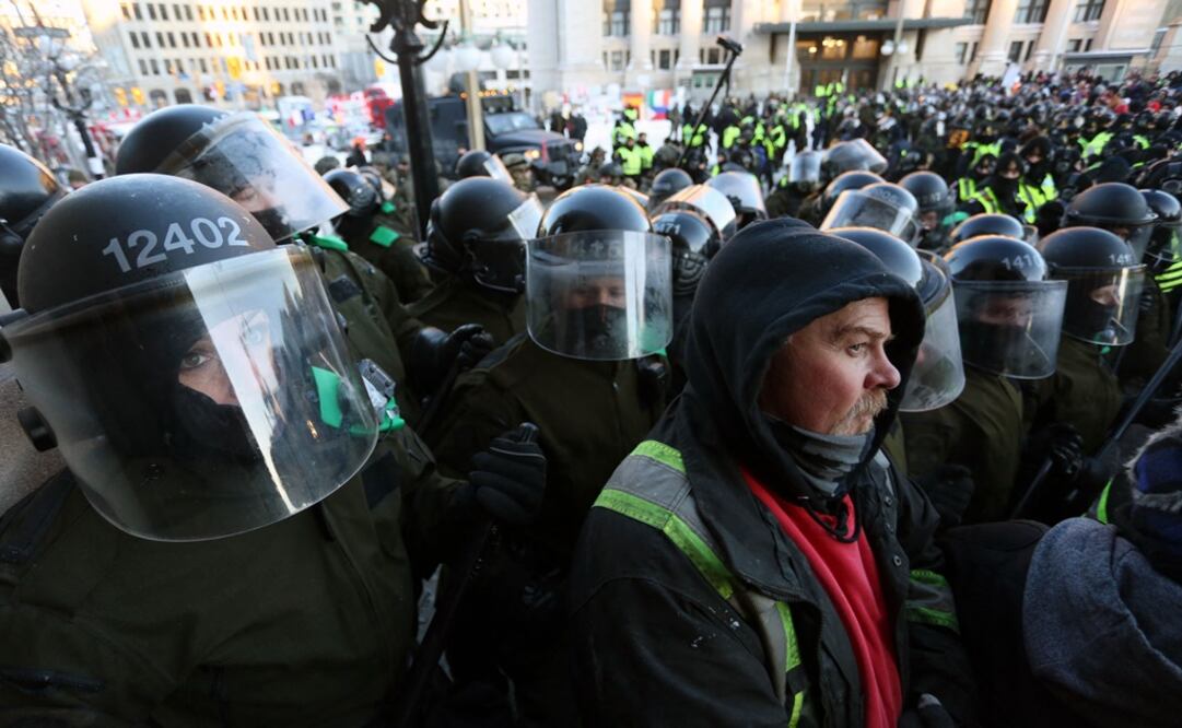 Manifestantes se mantienen firmes frente a una línea policial durante una protesta contra los mandatos de Covid-19 en Ottawa. Foto: AFP