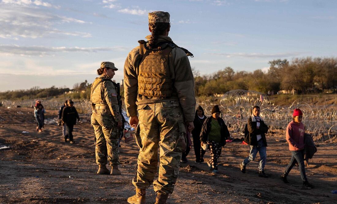Soldados de la Guardia Nacional de Texas observan a miles de migrantes dirigirse a un centro de tránsito en Eagle Pass, Texas. FOTO: JOHN MOORE. AFP