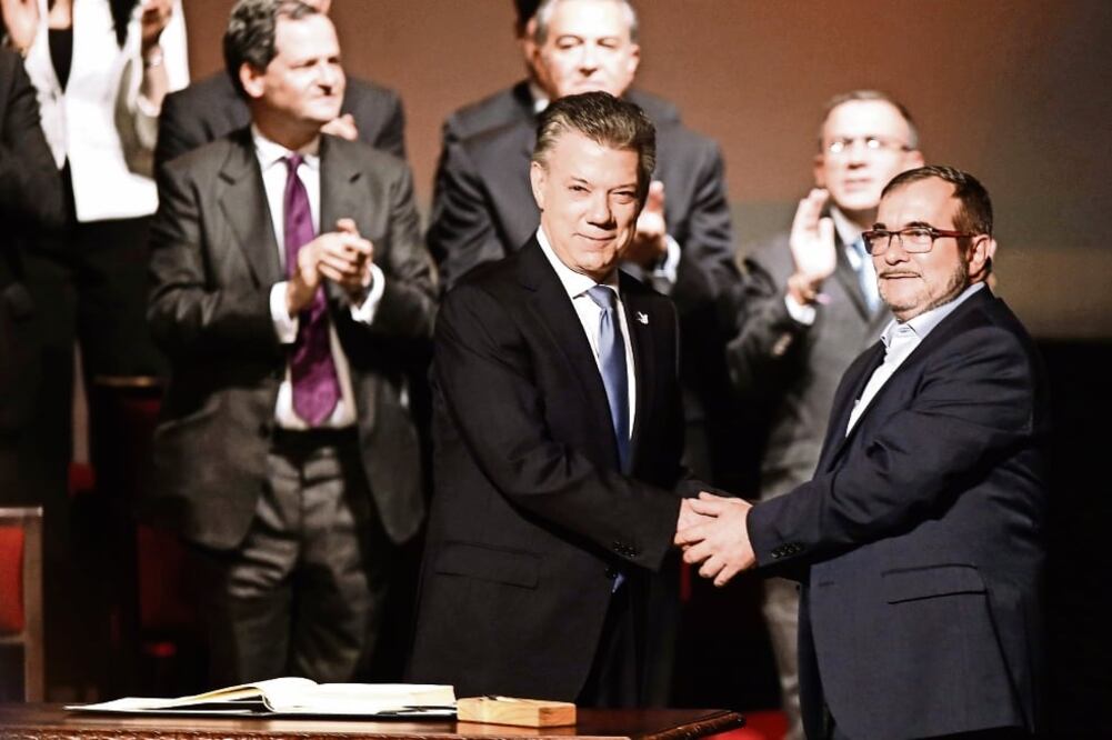 El presidente de Colombia, Juan Manuel Santos (izq.), estrecha la mano del jefe de las FARC, Rodrigo Londoño, en la ceremonia de ayer en el Teatro Colón. FOTO: JUAN PÁEZ. XINHUA