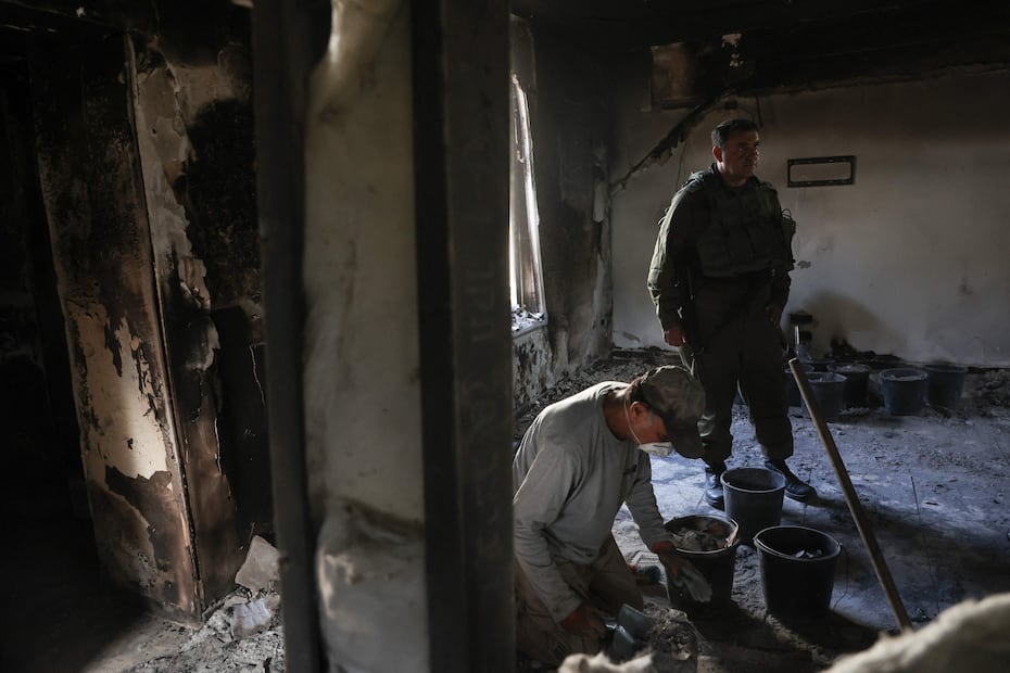 Soldado israelí cerca de arqueólogos de la Autoridad de Antigüedades de Israel, mientras recoge cenizas de una casa incendiada dentro del Kibbutz Nir Oz en el sur de Israel, para identificar a los residentes que desaparecieron durante el ataque del 7 de octubre a militantes de Hamas, el 9 de noviembre de 2023. Foto: GIL COHEN-MAGEN / AFP