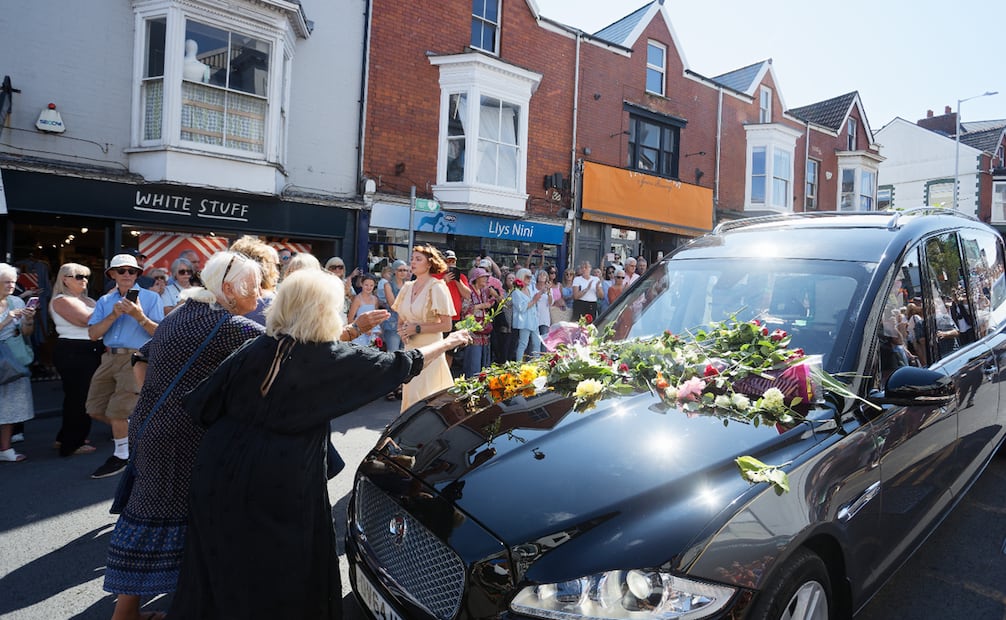 Seguidores rinden homenaje depositando flores al paso del coche fúnebre que traslada a la cantante galesa Bonnie Tyler por Newton Road hacia su domicilio en Llwynderw, Mumbles (Gales, Reino Unido).
Foto: EFE/EPA/DIMITRIS LEGAKIS.