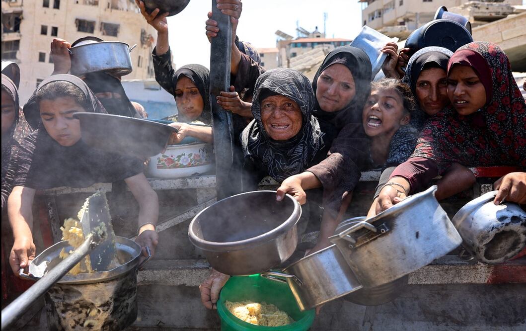 Mujeres y niñas palestinas se abren paso a codazos para recibir arroz cocido de un comedor social en la ciudad de Gaza, el 23 de agosto de 2025. Foto: AFP