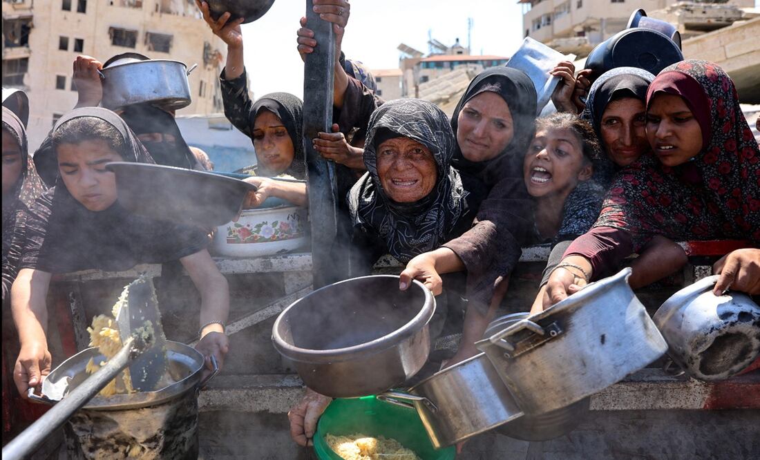 Mujeres y niñas palestinas se abren paso a codazos para recibir arroz cocido de un comedor social en la ciudad de Gaza, el 23 de agosto de 2025. Foto: AFP