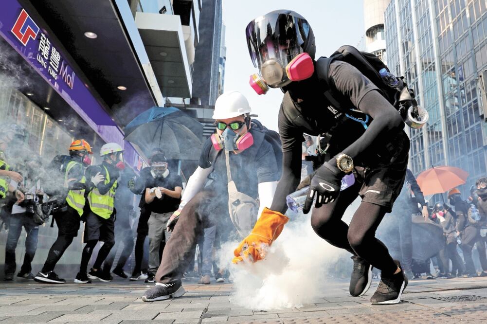 Enfrentamiento. Encapuchados riñeron con la policía en la avenida Nathan Road, en el distrito de Kowloon. Foto/TYRONE SIU. REUTERS