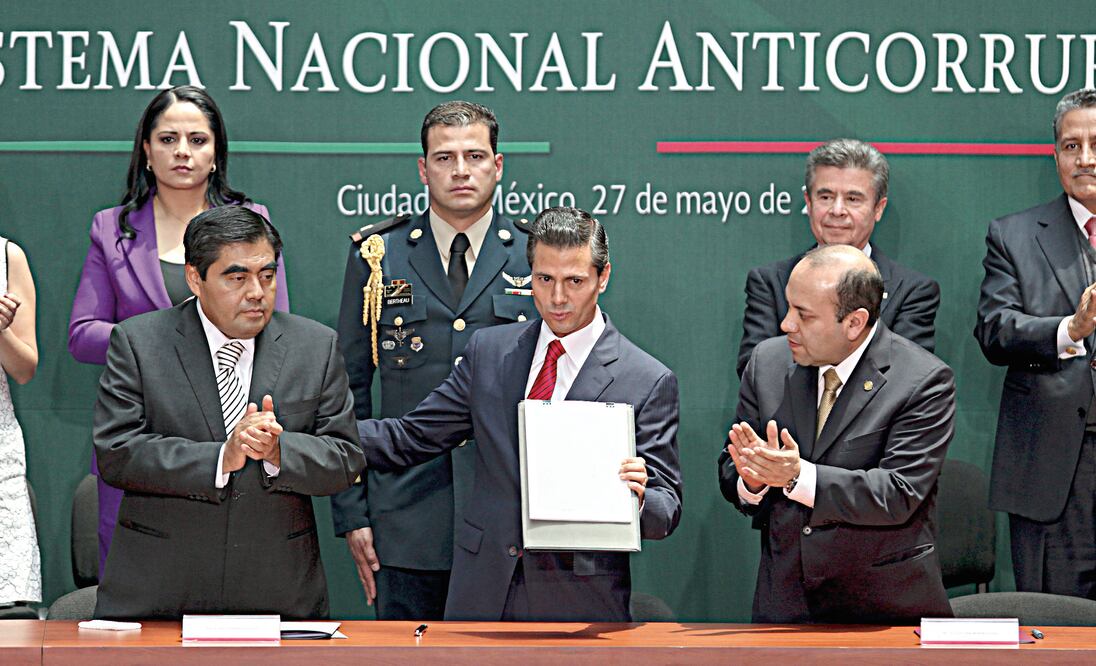El presidente Enrique Peña Nieto muestra el decreto de la reforma en materia de combate a la corrupción, durante una ceremonia en Palacio Nacional. Lo acompañan los presidentes del Senado, Miguel Barbosa, y de la Cámara de Diputados, Julio César Moreno