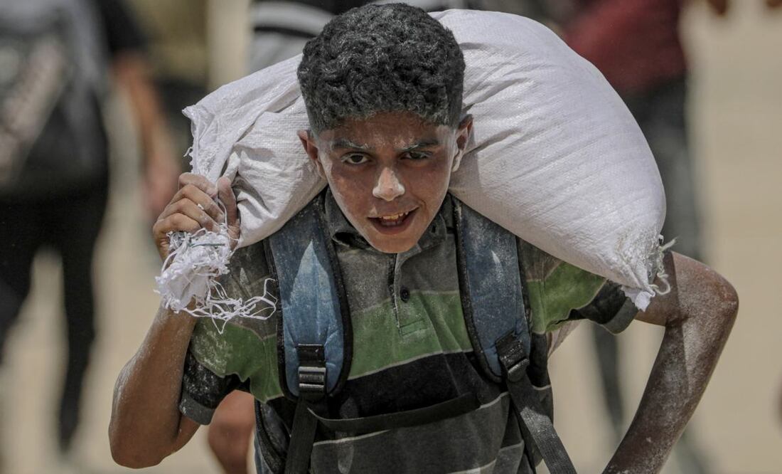 Un joven palestino lleva una bolsa de harina cerca de un punto de distribución de alimentos en Zikim este viernes, en el norte de la Franja de Gaza. Las organizaciones humanitarias han advertido de una catástrofe alimentaria inminente para miles de niños, una crisis provocada por la grave inseguridad alimentaria, el deterioro de los servicios sanitarios y las continuas restricciones a la ayuda humanitaria y los suministros esenciales. Foto: EFE