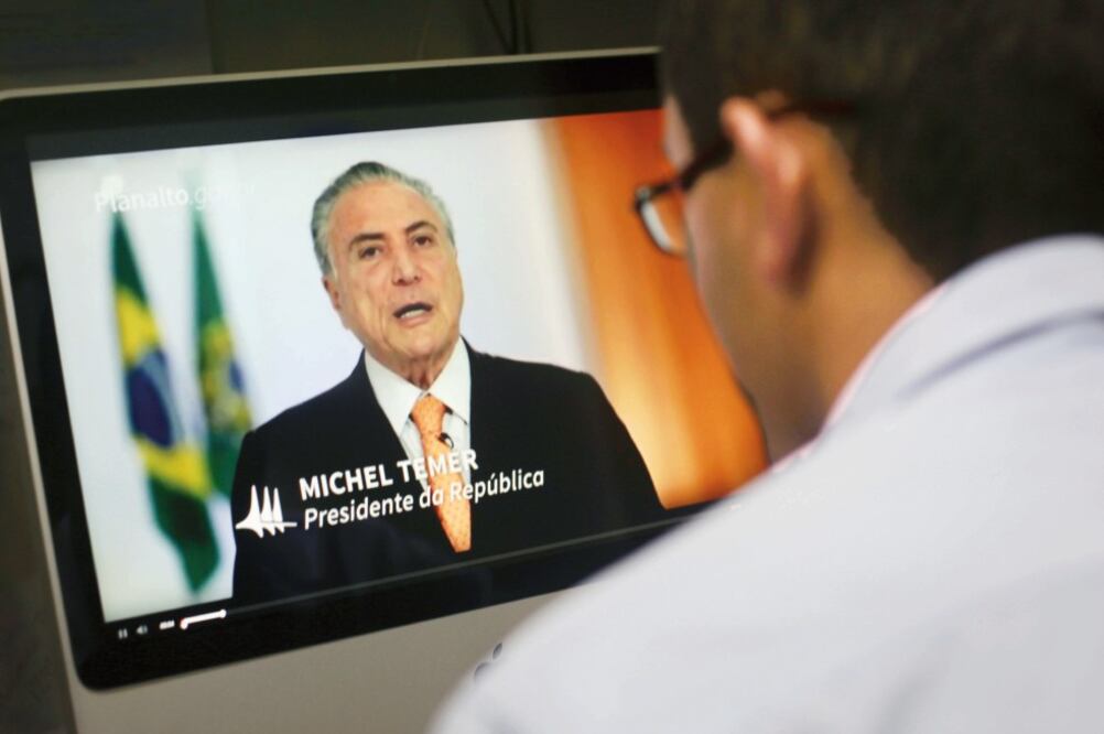 Un brasileño observa el video donde Temer niega haber acordado con la gente de Odebrecht sobornos a su partido, en 2010 (ERALDO PÉREZ. AP)