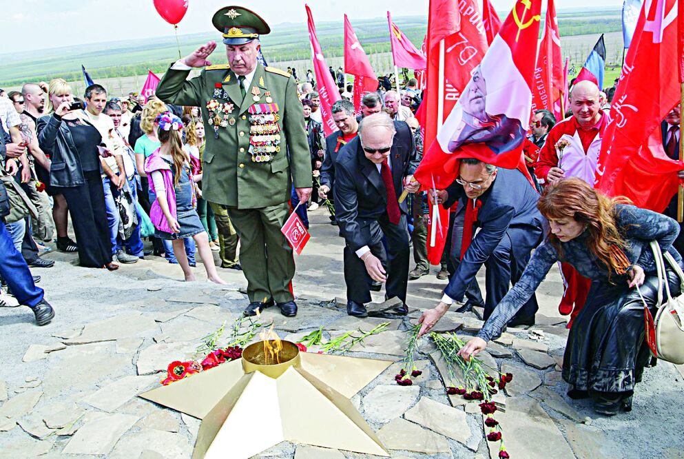 Un grupo de personas deposita flores en el monumento en memoria de los soldados del ejército rojo que murieron en la II Guerra Mundial, en Ucrania (ALEXANDER ERMOCHENKO / EFE)