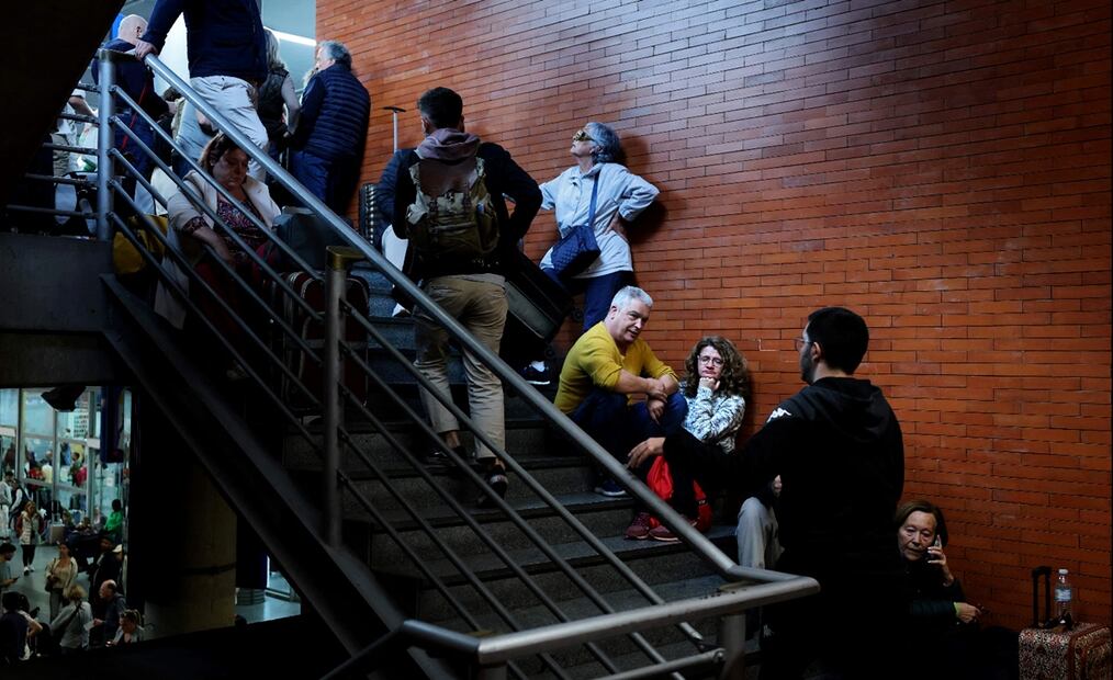 Pasajeros esperan sus trenes en una escalera en la estación de Atocha de Madrid el 29 de abril de 2025, un día después de un apagón masivo que afectó a toda la península Ibérica y al sur de Francia. Foto: AFP
