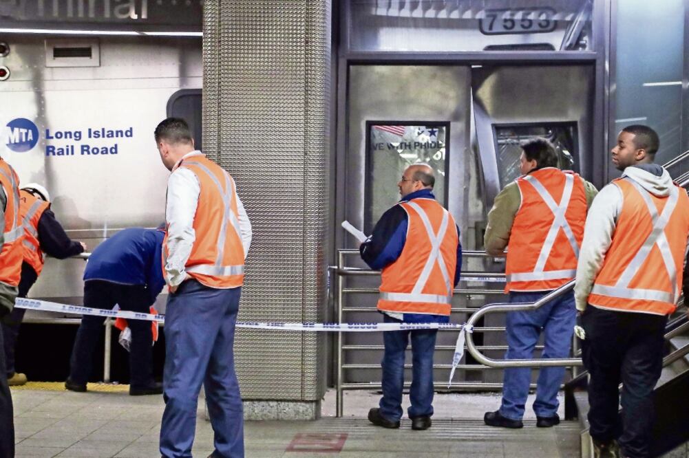 Oficiales de policía y operarios observan los daños tras el accidente de un tren en la estación de Atlantic en el distrito de Brooklyn, Nueva York. (ANDREW GOMBERT. EFE)