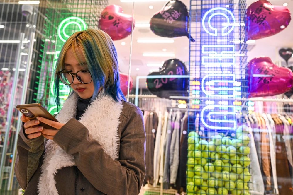 Wang Xiuting chatea con su novio virtual en Wantalk -un chatbot de inteligencia artificial creado por la empresa tecnológica china Baidu- en su teléfono en un centro comercial de Beijing. FOTO: JADE GAO. AFP