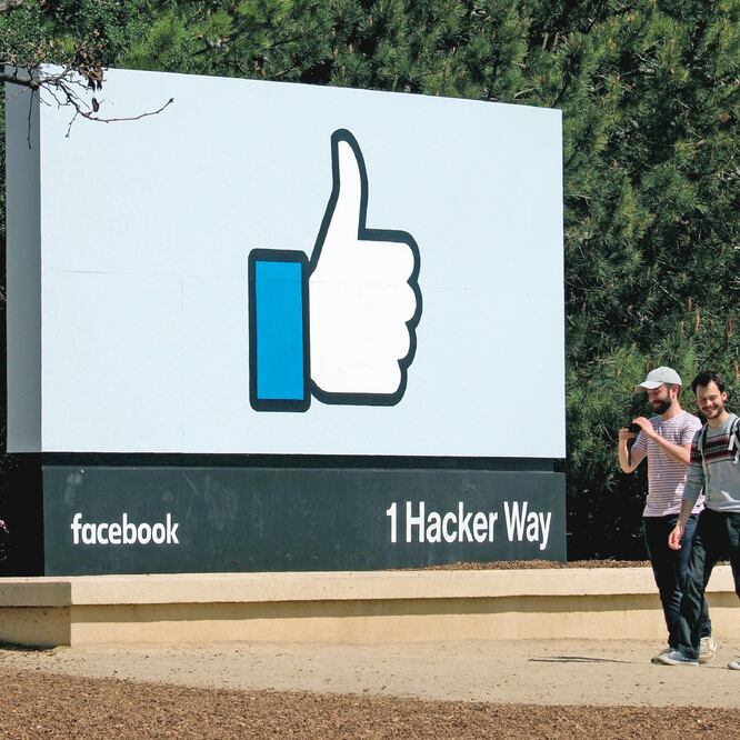 Dos jóvenes caminan junto a un icono de Facebook en Menlo Park, California. La red social dijo que enviaría mensajes a 30 millones de víctimas de los hackers. (JOHN G. MABANGLO. EFE)