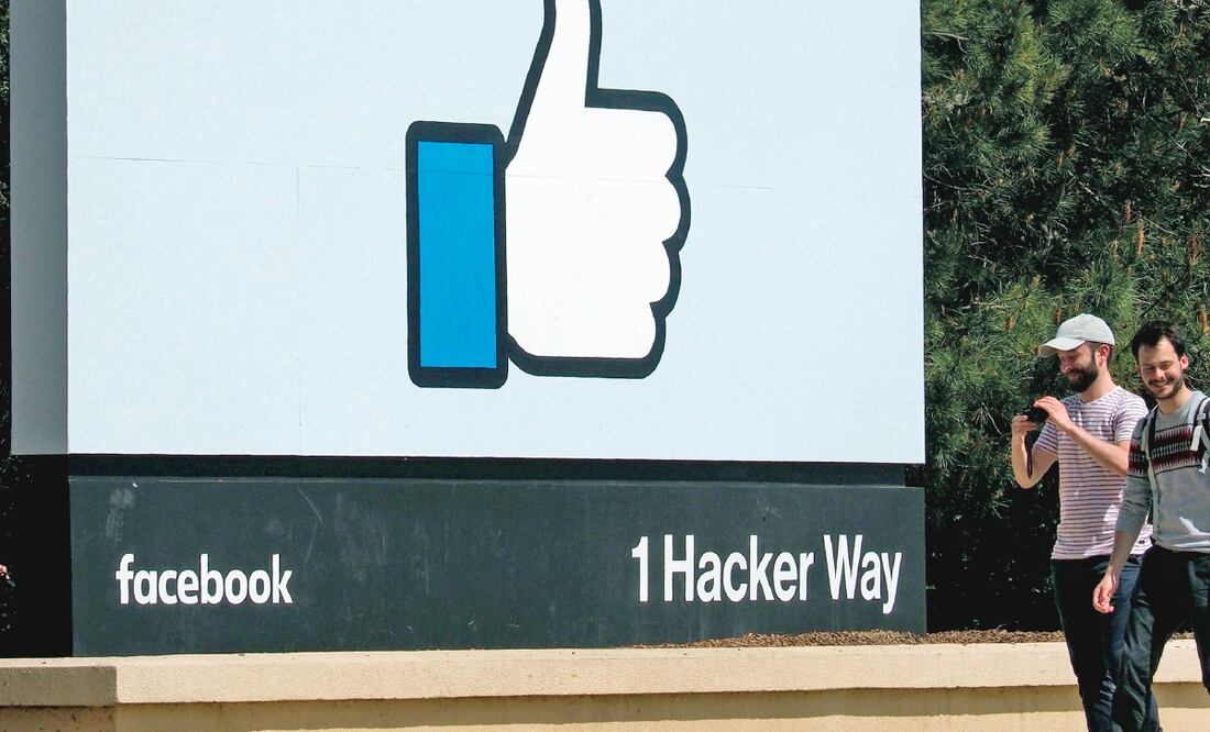 Dos jóvenes caminan junto a un icono de Facebook en Menlo Park, California. La red social dijo que enviaría mensajes a 30 millones de víctimas de los hackers. (JOHN G. MABANGLO. EFE)