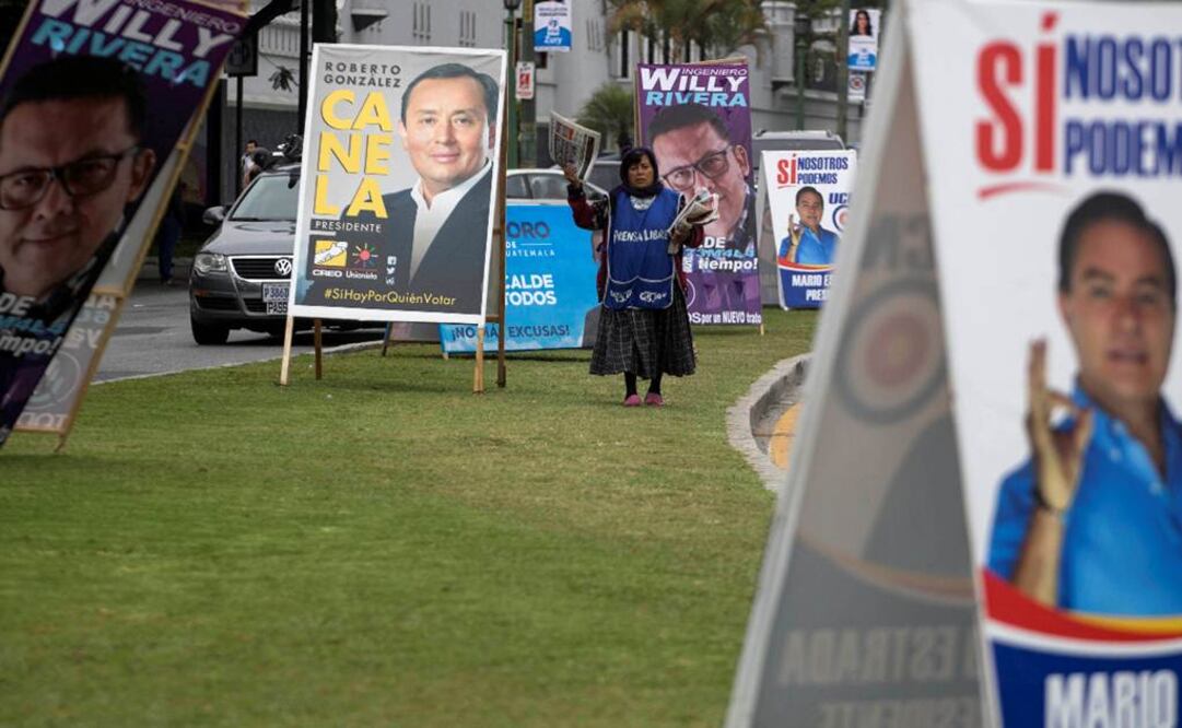 Una vendedora de diarios camina por una calle con propaganda de los candidatos presidenciales y locales, en Ciudad de Guatemala Foto: AP