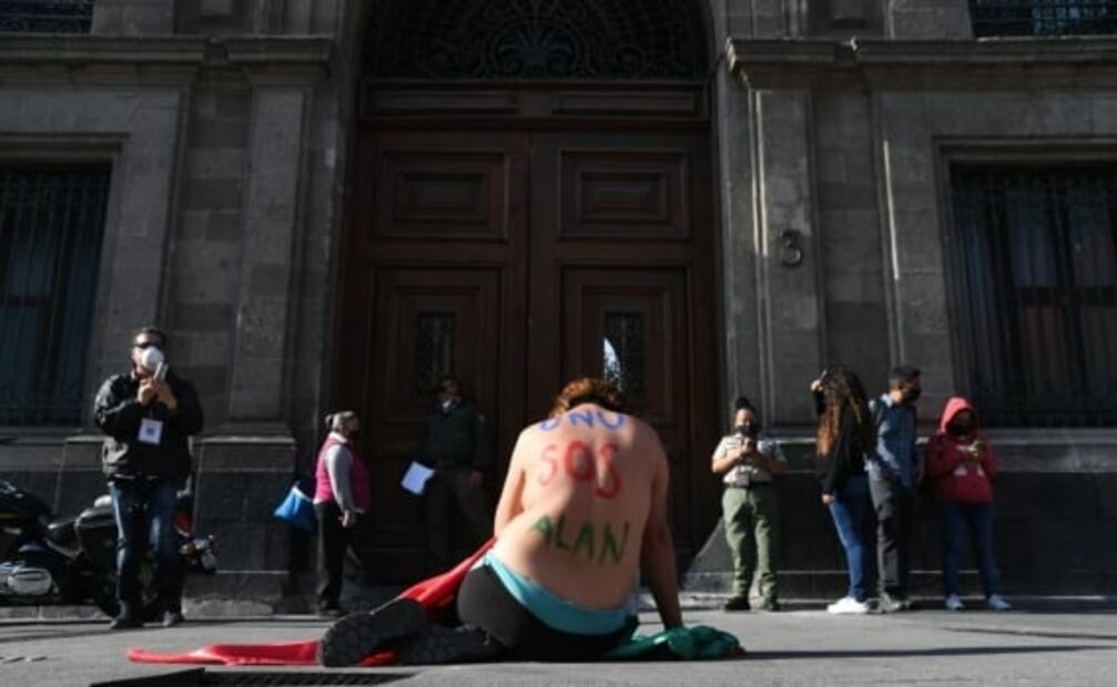Mujer envuelta en bandera frente a Palacio Nacional exige justicia para su hijo asesinado
