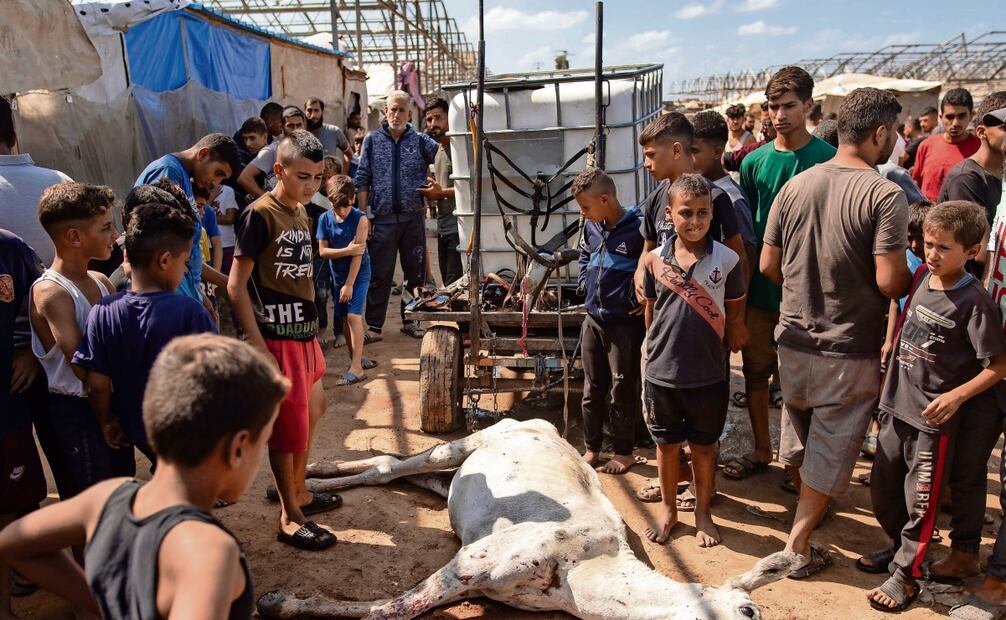 Palestinos pasan junto a una casa destruida tras un ataque aéreo de Israel en la Franja de Gaza. Foto: Mohamed Saber / EFE