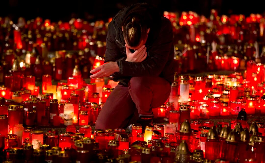 Un hombre se arrodilla en medio de un altar conmemorativo por las personas que fallecieron en un incendio en el club nocturno Colectiv, en Bucarest, Rumania (Foto: AP)