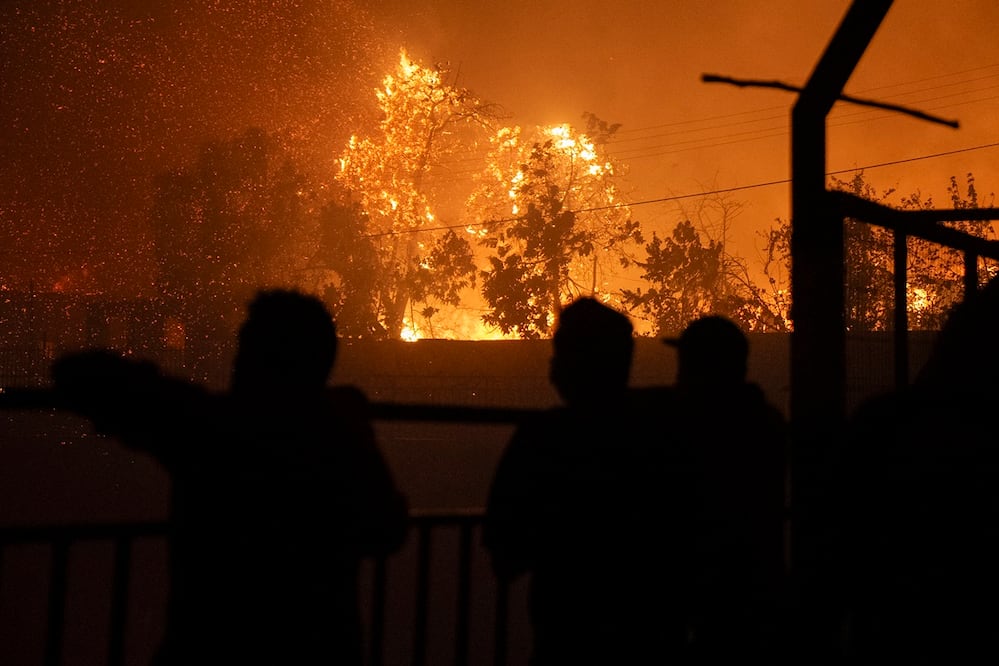 Personas observan un incendio que comenzó en la reserva natural del lago Peñuelas y ha llegado hasta las zonas urbanas, en Viña del Mar. Foto: EFE