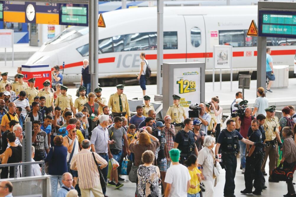 Policías escoltan a migrantes provenientes de Budapest en la estación central de Múnich. Cientos de personas llegan a esta ciudad alemana cada día, después de realizar peligrosas travesías desde sus países de origen (MATTHIAS SCHRADER. AP)