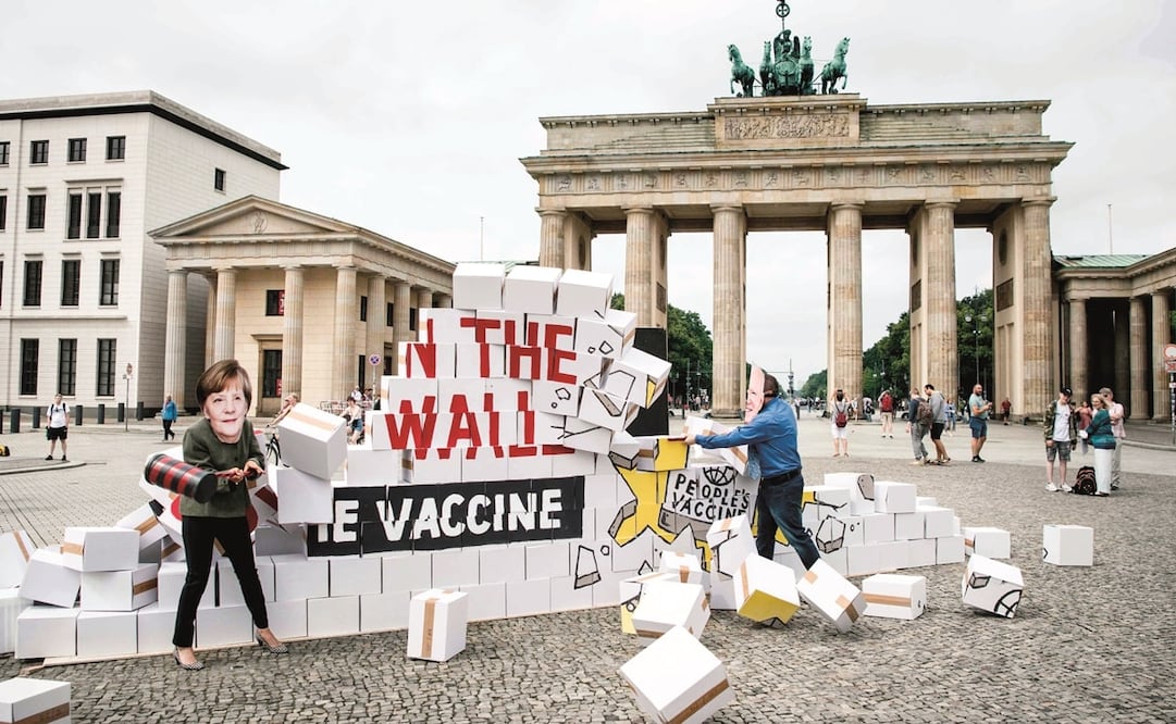 Activistas, con máscaras de la canciller Angela Merkel y el presidente Joe Biden, durante una protesta bajo el lema “Liberar la vacuna”, en Berlín. Foto: Stefanie Loos/AFP.