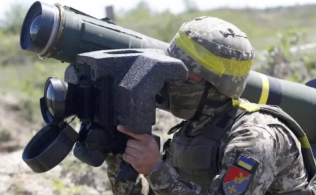 Foto: BBC News Mundo/ Junto a los restos quemados de un tanque ruso, un soldado ucraniano exhibe el armamento que, asegura, lo destruyó