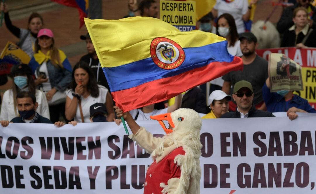 Una persona disfrazada ondea una bandera durante una protesta contra una reforma fiscal propuesta por el gobierno del presidente izquierdista Gustavo Petro. Foto: AFP