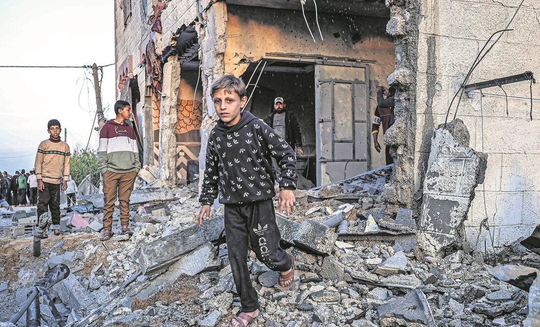 Palestinos caminan entre los escombros de un edificio dañado por bombardeos israelíes, en Rafah, en el sur de la Franja de Gaza. Foto: AFP