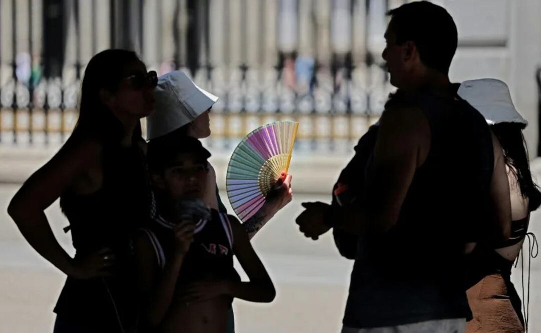 Turistas se abanican a la sombra. Foto: AFP