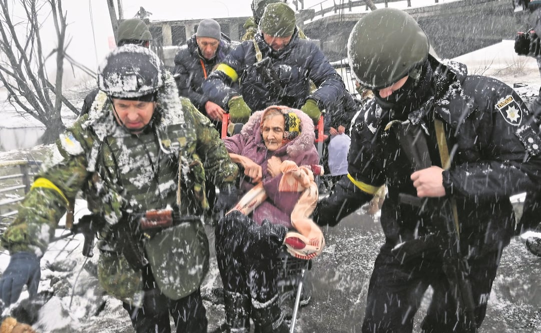 Soldados ucranianos ayudan a una mujer a cruzar un puente destruido en Irpin, al noroeste de Kiev. Más de 2 millones de personas han huido desde que Rusia lanzó su invasión, indicó ACNUR. Foto: SERGEI SUPINSKY. AFP