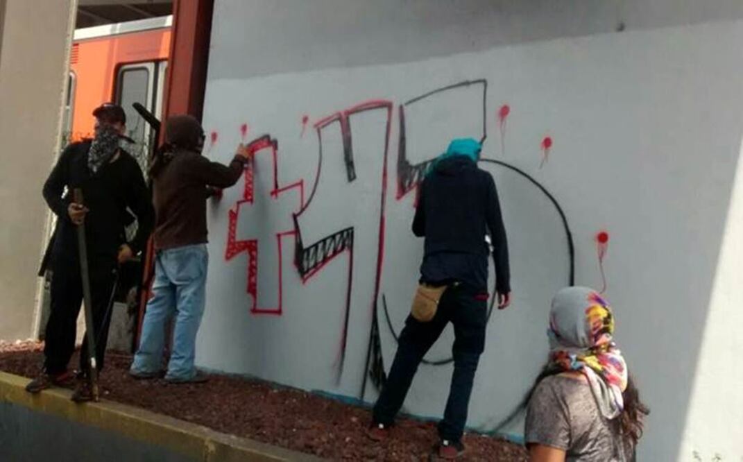 Un grupo de jóvenes encapuchados, quienes marchan en la Jornada de Acción Global por Ayotzinapa, realizaron pintas en la calzada de Tlalpan