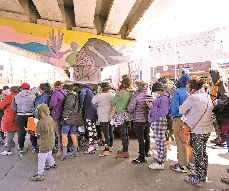 Migrantes que esperan del lado mexicano de la frontera para poder cruzar a Estados Unidos hacen fila para recibir comida en Tijuana. Foto: GREGORY BULL. AP