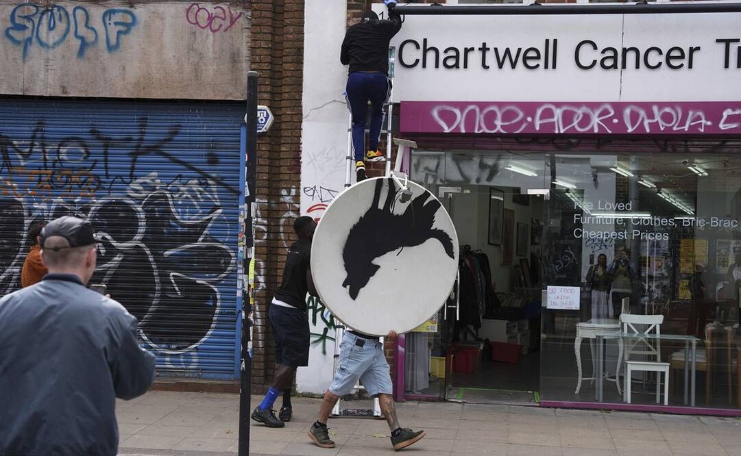 La gente retira una nueva obra de arte de Banksy. Foto: AP