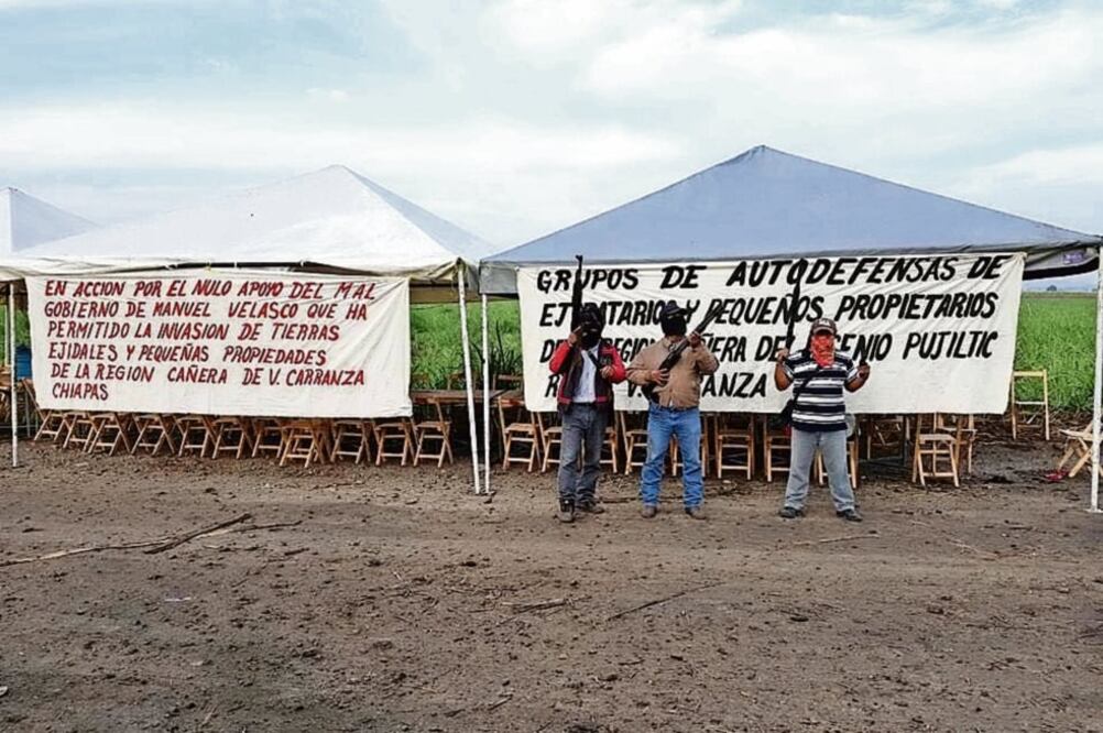 En una foto que empresarios mandaron a medios de comunicación, se observa a tres sujetos armados y atrás hay mantas de los autodefensas (FREDY MARTÍN. EL UNIVERSAL)