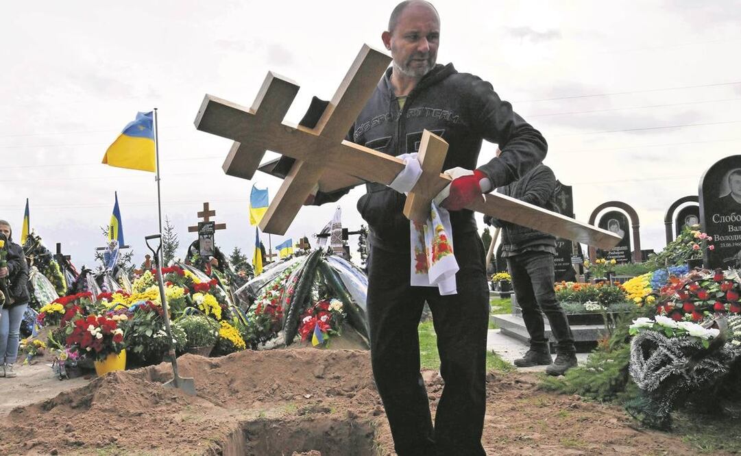Un trabajador lleva una cruz al funeral de Mykhaylo Matyushenko, coronel del ejército ucraniano derribado sobre el mar Negro en junio. Foto: Serguéi Supinsky/ AFP