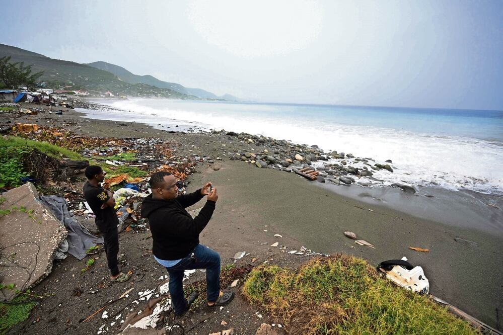 Lugareños observan cómo las olas rompen en la playa en East Kingston, Jamaica. Foto: Ricardo Makyn | AFP