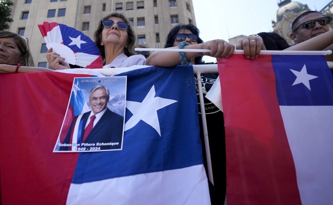 Chilenos se encuentran detrás de una valla afuera del palacio presidencial de La Moneda esperando la llegada del ataúd del expresidente Sebastián Piñera en Santiago, Chile. Foto: AP