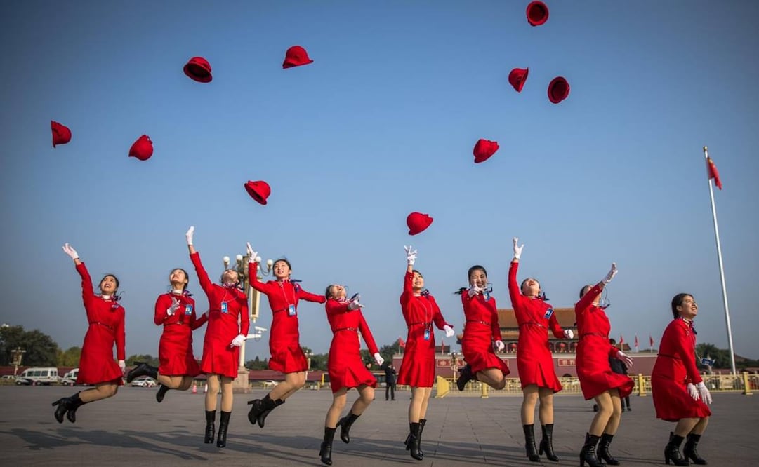 Azafatas chinas lanzan sus sombreros al aire mientras posan para una fotografía en la Plaza Tiananmen, antes de la ceremonia de clausura del Congreso Nacional del Partido Comunista de China, en 2017. EFE
