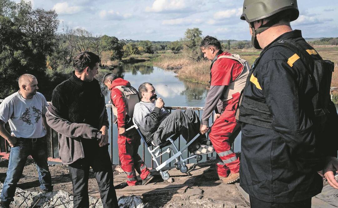Un ucraniano es transportado para cruzar el puente destruido por combates sobre el río Oskil mientras desalojan la orilla este recuperada en Kupiansk, Kharkiv.Foto: Yasuyoshi Chiba/AFP