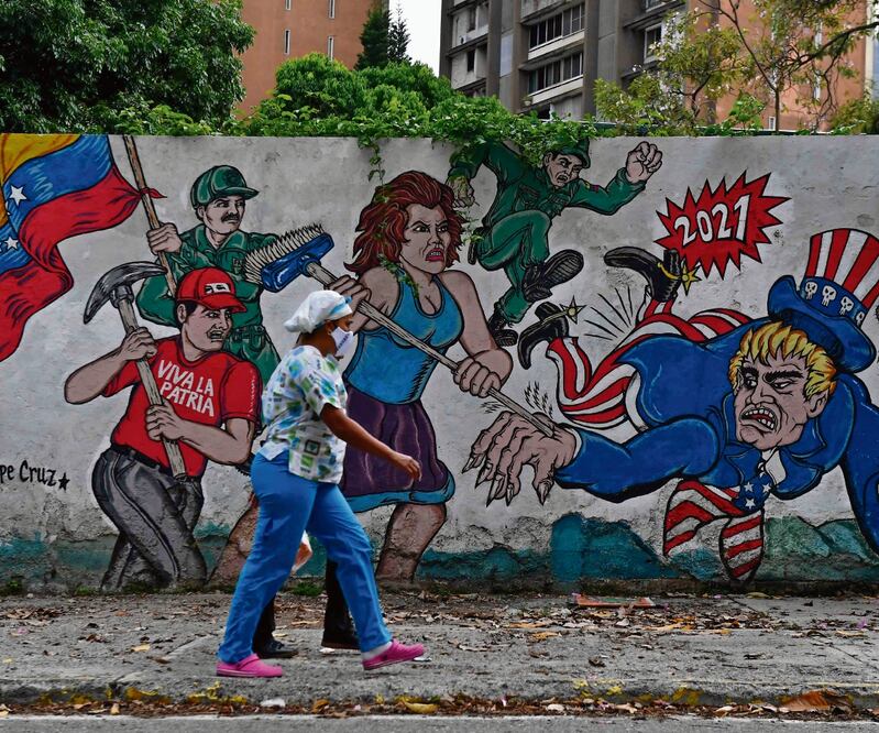 Una mujer camina frente a un graffiti en Caracas que muestra al Tío Sam (Estados Unidos) atacado. Washington confirmó que el régimen de Nicolás Maduro no fue invitado a la Cumbre de las Américas. Foto: Federico Parra/AFP