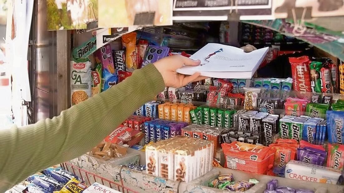 La encargada de un comercio recibe una copia de la nueva propuesta de la Constitución, en Santiago, el 14 de noviembre pasado. Foto: EFE