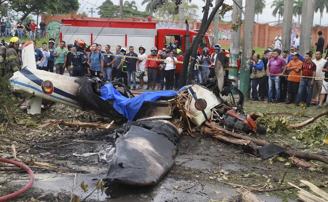 Vecinos observan los restos de un avión de la Fuerza Aérea Colombiana que se estrelló en una zona urbana de Cali, Colombia. Foto: AP