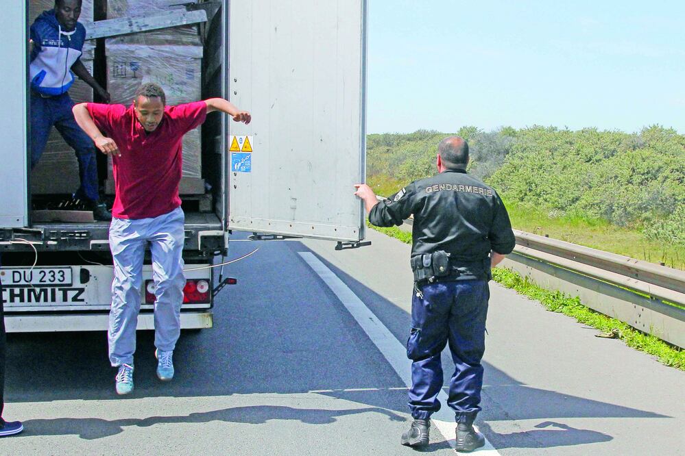 Un migrante salta de un camión en Calais tras ser descubierto por la policía francesa, en un intento fallido por cruzar el Canal de la Mancha, ayer (MICHEL SPINGLER / AP)