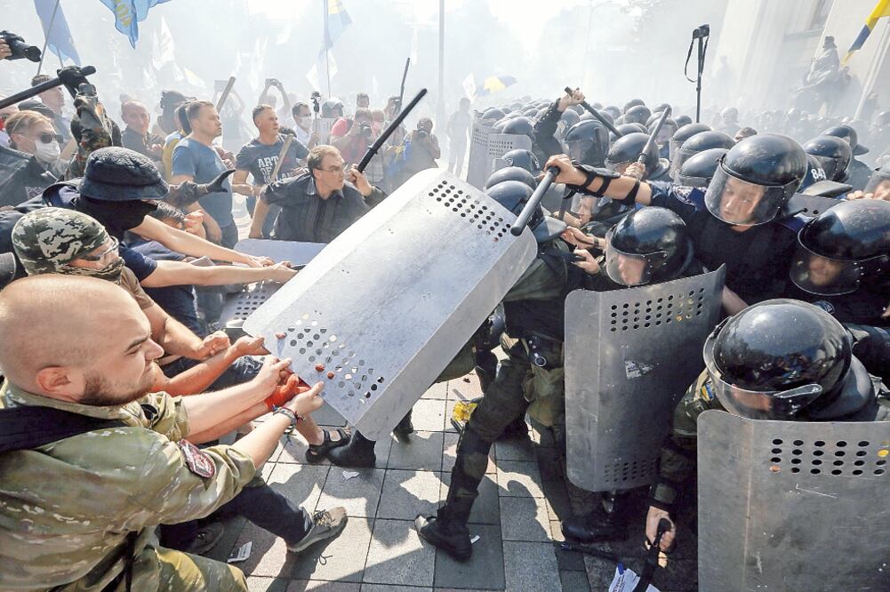 Opositores a la reforma constitucional, que contempla un régimen de autogobierno en determinadas zonas de Donetsk y Luhansk, se enfrentaron ayer a la policía ante el Parlamento ucraniano en Kiev (SERGEY DOLZHENKO. EFE)