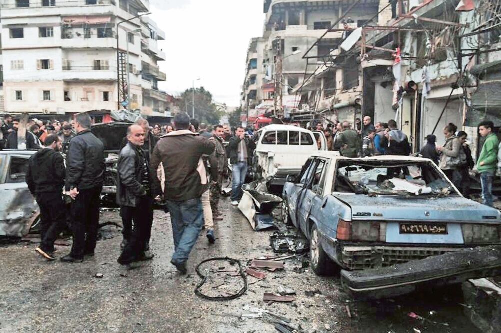 Ciudadanos sirios observan la zona donde explotó un coche-bomba en la localidad e Jableh, bajo control de las autoridades de Damasco, que dejó un saldo de 15 muertos (AP)