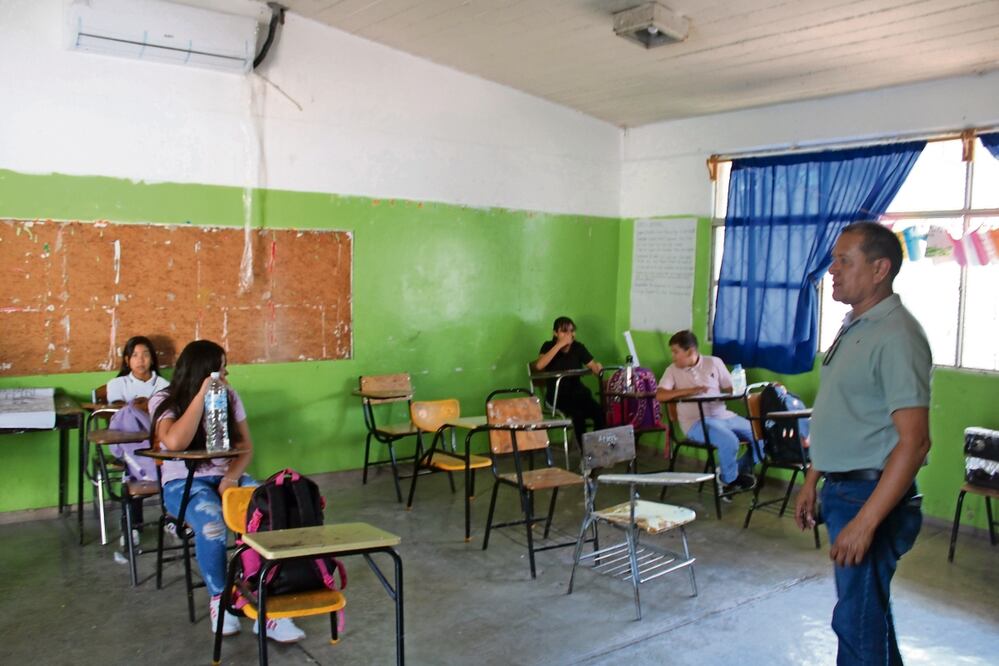 En los pupitres, los cinco alumnos intentan refrescarse con agua, y sustituyen los ventiladores con hojas de cuaderno para soportar el calor. Foto: Francisco Rodríguez | El Universal